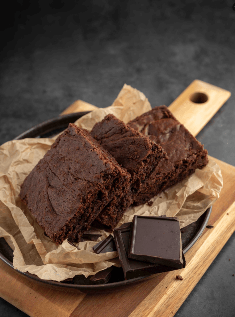 Thick, fudgy chocolate brownies on parchment paper with dark chocolate pieces on the side.